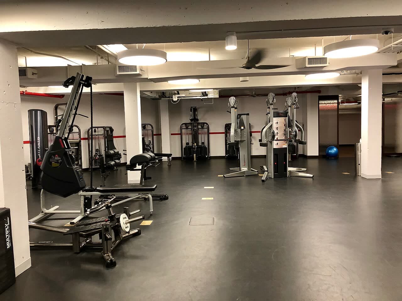 A hotel gym with weight machines under ceiling lights
