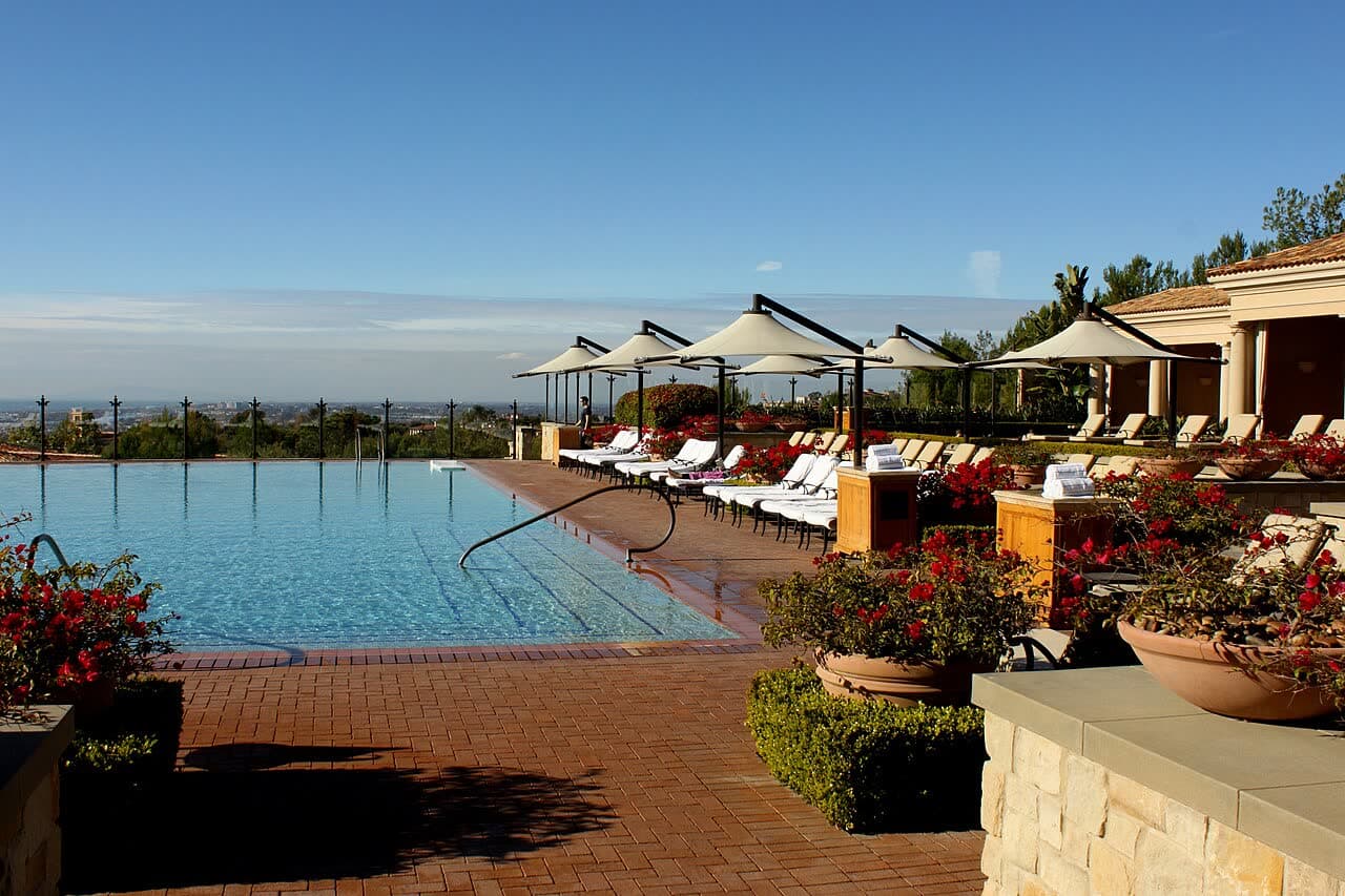 An infinity pool with sun loungers and umbrellas at a resort